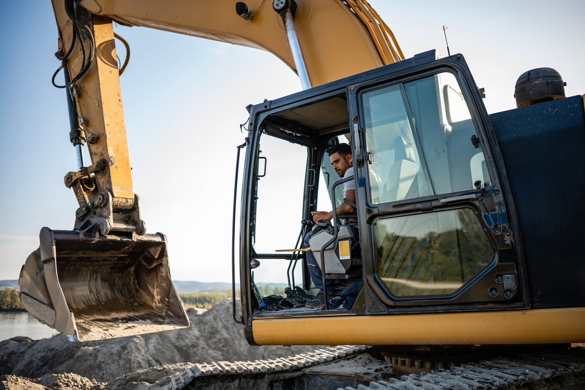Large excavator on a commercial earthworks site beside a river