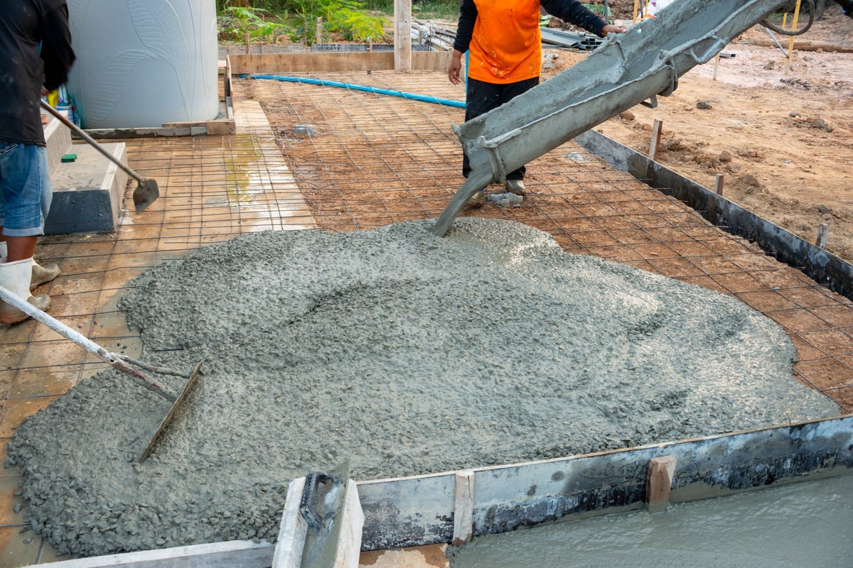 Workers pouring concrete to form a solid house slab foundation on a construction site