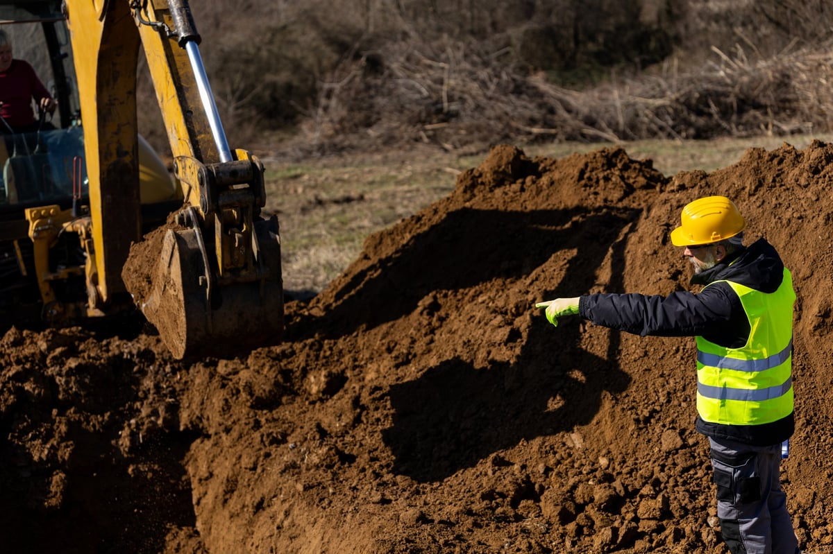 Worker guiding an excavator during excavation in Geelong