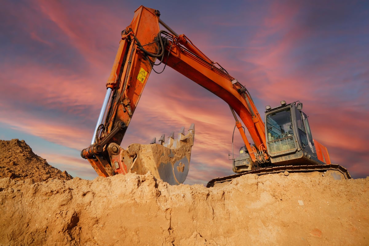 Excavator moving soil at sunset on a Geelong earthworks project
