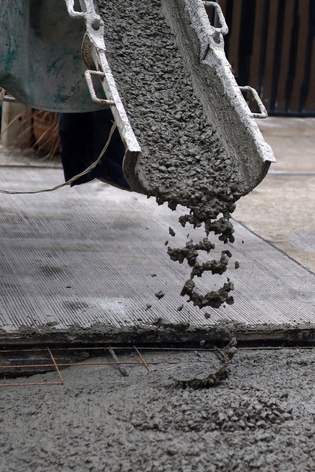 Wet concrete pouring from a mixer truck onto steel reinforcement mesh for a foundation