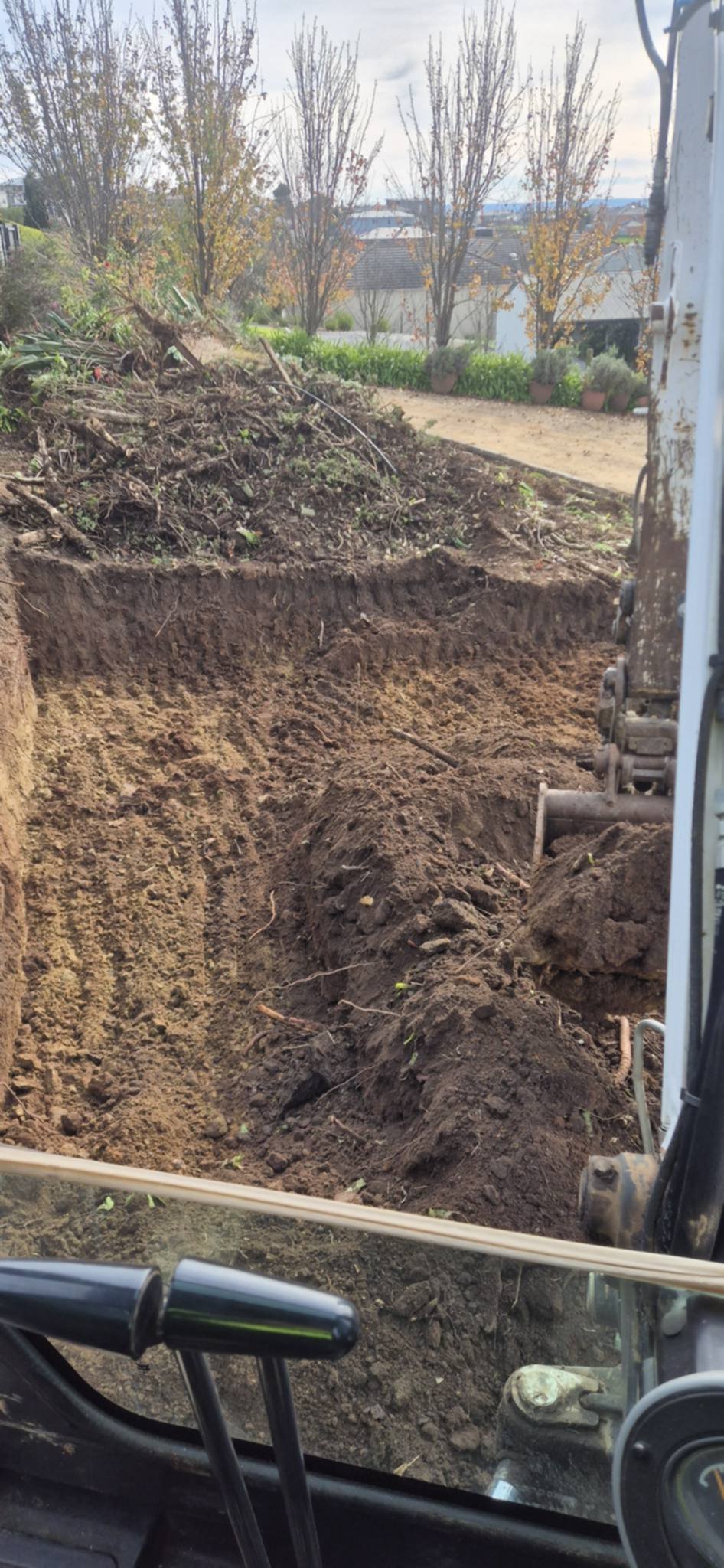 Excavated dirt trench with poplar trees and river landscape in the background